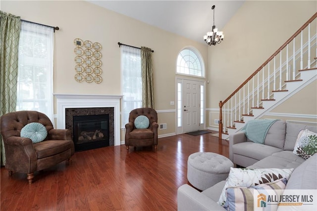 704 Schindler Dr, South Brunswick, NJ 08852 - living area featuring a chandelier, wood finished floors, stairway, a glass covered fireplace, and high vaulted ceiling