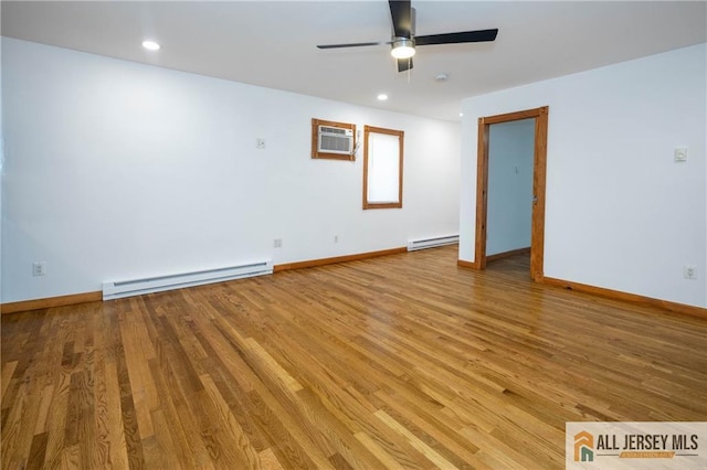 spare room with ceiling fan, a baseboard heating unit, wood finished floors, and baseboards