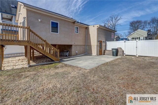 rear view of house featuring a patio, stairs, fence, and a gate