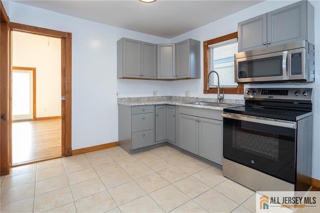 kitchen with gray cabinets, a sink, light countertops, and stainless steel appliances