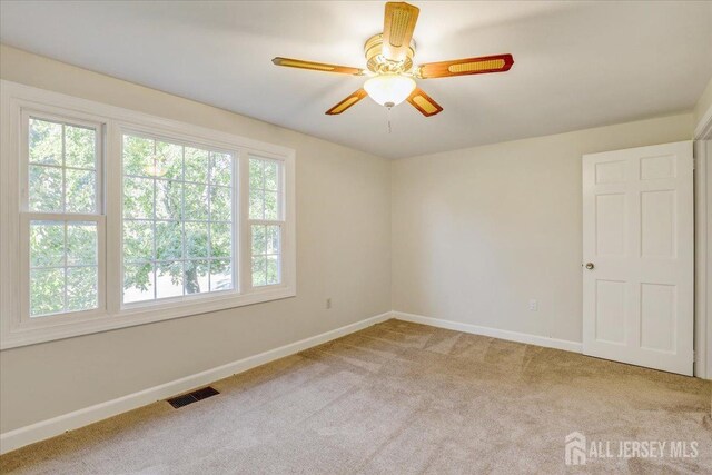 carpeted spare room featuring ceiling fan