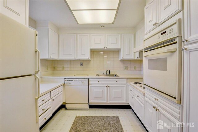 kitchen featuring white cabinets, decorative backsplash, white appliances, and sink