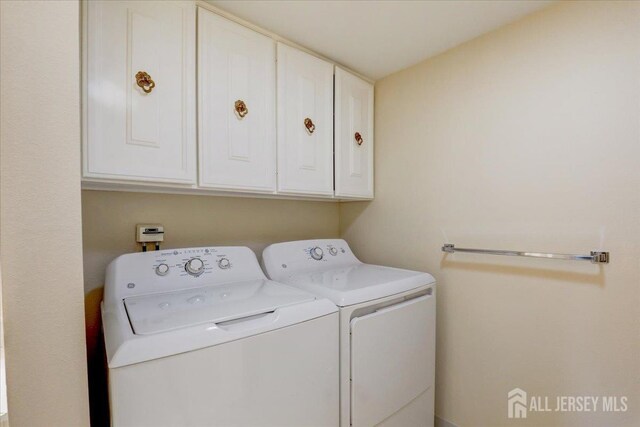 clothes washing area featuring cabinets and washing machine and dryer