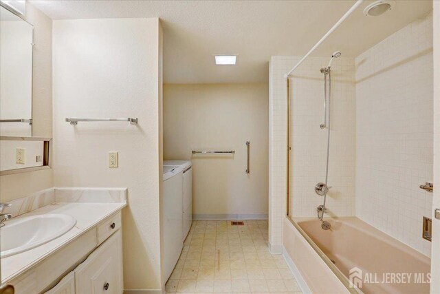 bathroom featuring washer and dryer, tiled shower / bath, and vanity