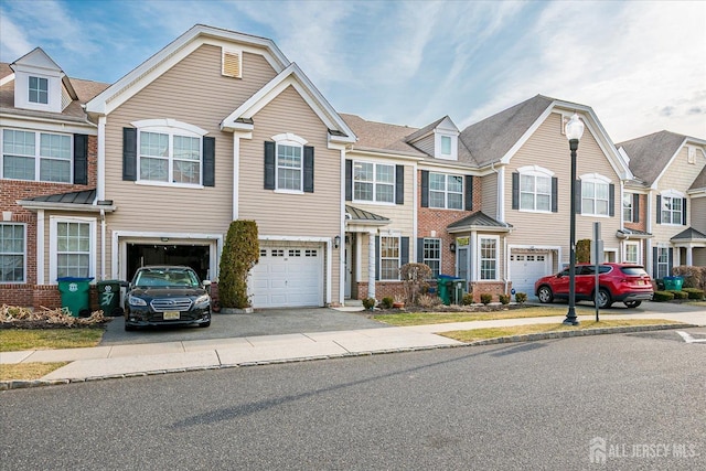 townhome / multi-family property featuring a residential view, brick siding, a garage, and driveway