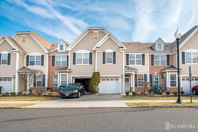 multi unit property with brick siding, driveway, and a garage