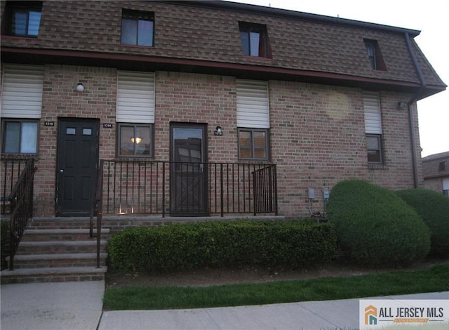 view of front of home featuring brick siding and mansard roof