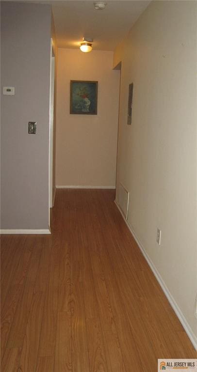 corridor featuring baseboards and wood finished floors
