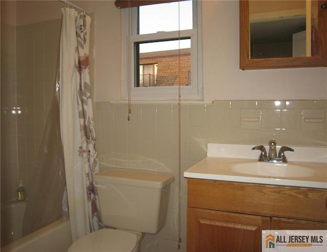 full bathroom with vanity, shower / tub combo, toilet, and tile walls