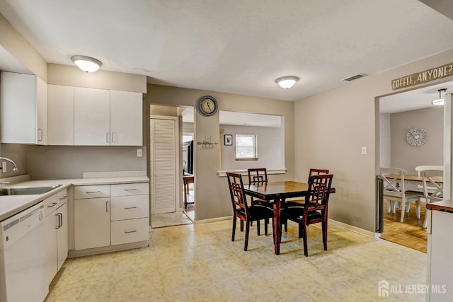 kitchen featuring light parquet floors, sink, white dishwasher, and white cabinetry