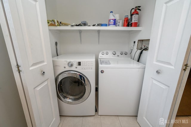 washroom with light tile patterned floors, laundry area, and washer and clothes dryer