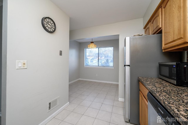 kitchen featuring light tile patterned floors, baseboards, visible vents, dark stone countertops, and stainless steel appliances