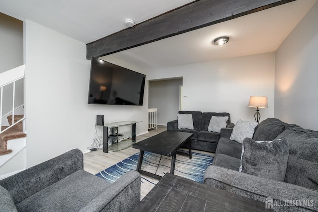 living area with beam ceiling, stairway, baseboards, and wood finished floors