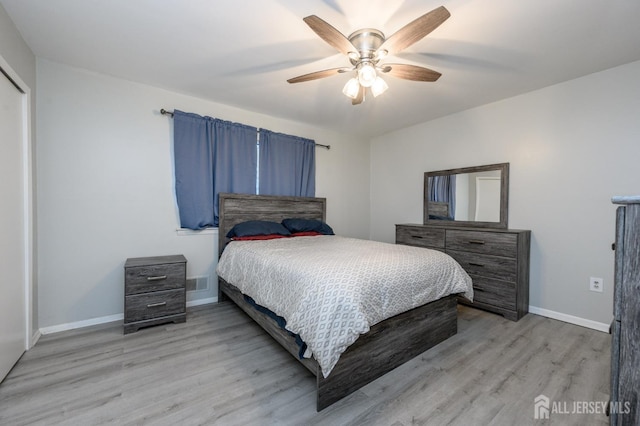 bedroom featuring a ceiling fan, visible vents, light wood-style flooring, and baseboards