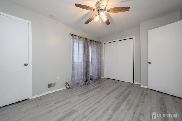 unfurnished bedroom featuring baseboards, visible vents, a ceiling fan, wood finished floors, and a closet