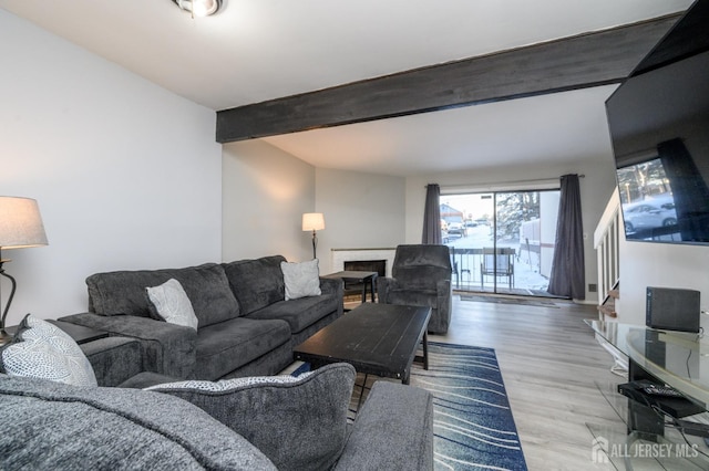 living area with a fireplace, beamed ceiling, and wood finished floors