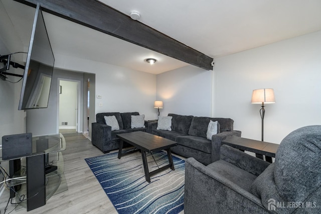 living area with wood finished floors and beam ceiling