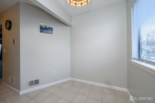 empty room featuring baseboards, visible vents, and light tile patterned flooring