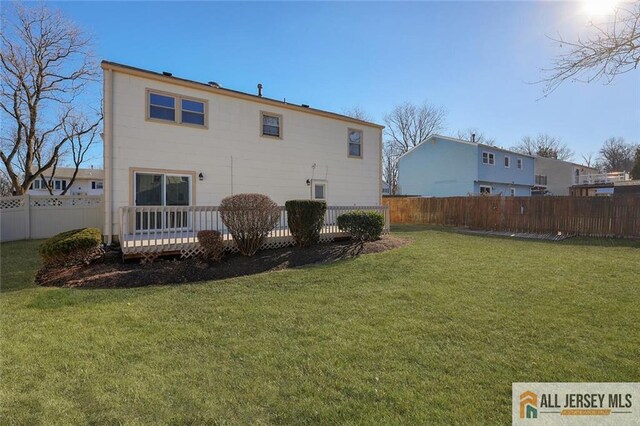 rear view of house with a lawn and a wooden deck