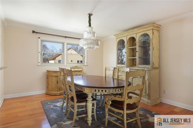 dining space featuring light hardwood / wood-style floors, crown molding, and a chandelier