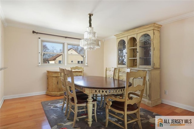 dining area with crown molding, a chandelier, and light hardwood / wood-style floors