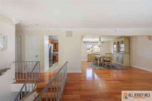 interior space featuring ornamental molding and light wood-type flooring