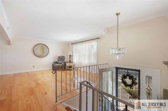 hallway with a notable chandelier, crown molding, and light hardwood / wood-style flooring