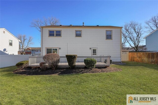 back of property featuring a lawn and a deck