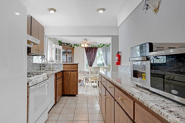 kitchen with exhaust hood, ceiling fan, light tile patterned floors, tasteful backsplash, and white gas stove