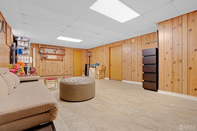 interior space with a drop ceiling and wood walls