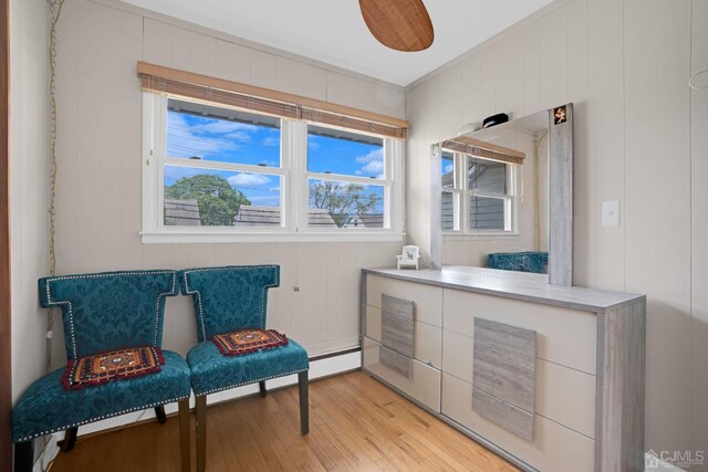 sitting room featuring wooden walls, ceiling fan, and light wood-type flooring