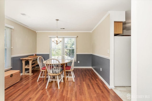 dining area with crown molding, hardwood / wood-style flooring, and an inviting chandelier