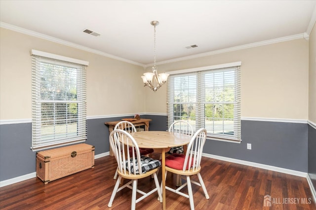 dining area featuring dark hardwood / wood-style flooring, ornamental molding, and an inviting chandelier