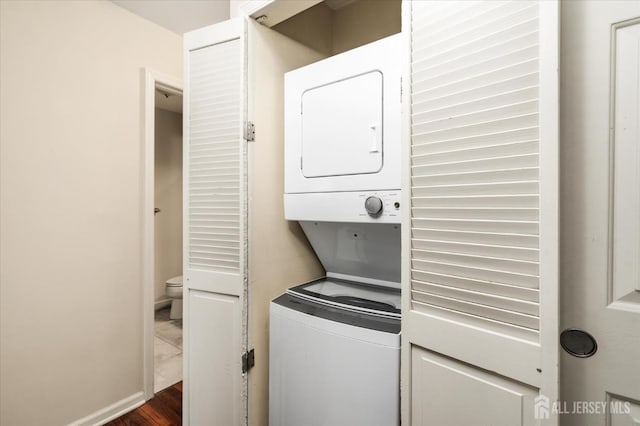 clothes washing area featuring dark hardwood / wood-style floors and stacked washing maching and dryer