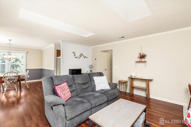 living room with an inviting chandelier, ornamental molding, dark hardwood / wood-style floors, and a skylight