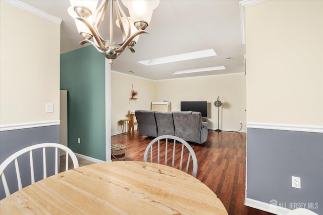 dining space with crown molding, dark wood-type flooring, a notable chandelier, and a skylight