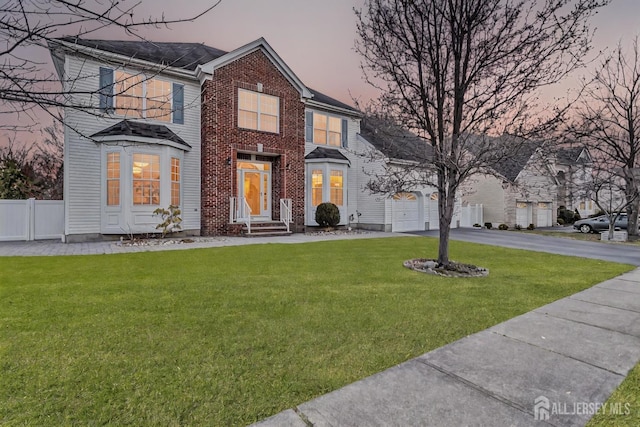57 Cortland Dr N, East Brunswick, NJ 08816 - view of front of property with a garage, fence, aphalt driveway, a front lawn, and brick siding