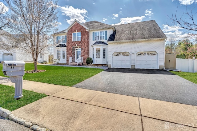 57 Cortland Dr N, East Brunswick, NJ 08816 - colonial home featuring an attached garage, fence, a front lawn, brick siding, and driveway