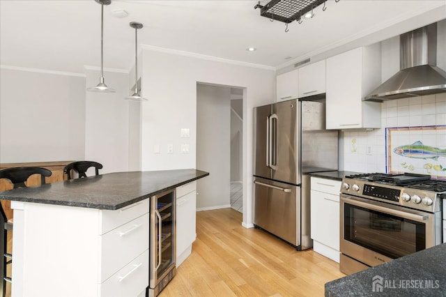 kitchen with stainless steel appliances, white cabinetry, a kitchen breakfast bar, and wall chimney exhaust hood