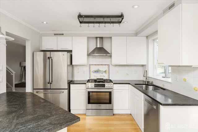 kitchen featuring wall chimney exhaust hood, sink, light wood-type flooring, stainless steel appliances, and white cabinets