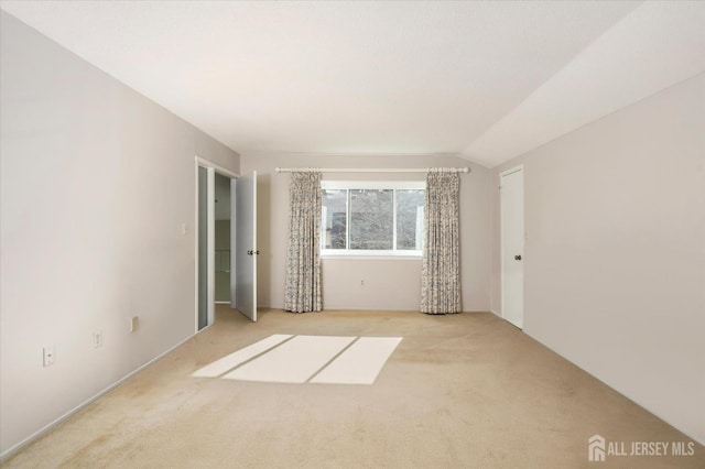 unfurnished room with lofted ceiling and light colored carpet