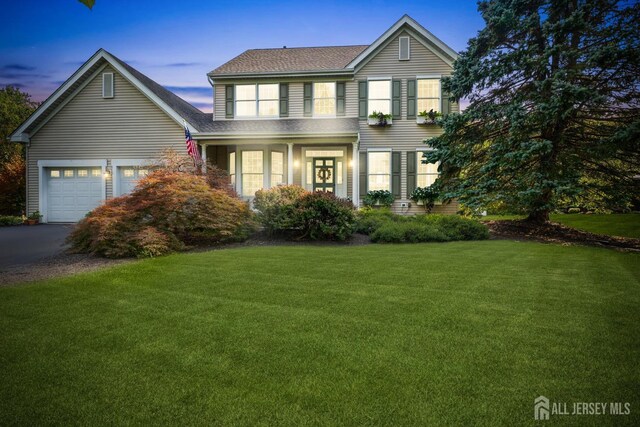 traditional home with aphalt driveway, a yard, and a garage