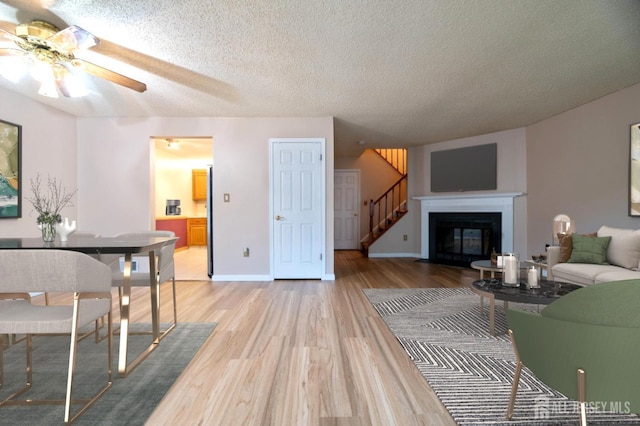 125 Albury Way N, Brunswick, NJ 08902 - living room with a ceiling fan, light wood-style floors, stairway, a textured ceiling, and a fireplace with flush hearth