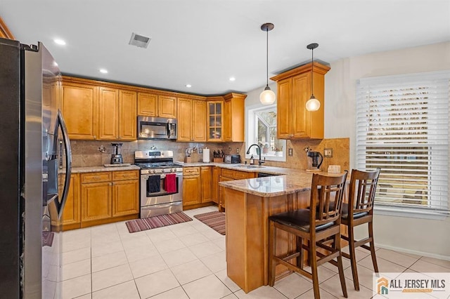3 Eric Ct, Monroe, NJ 08831 - kitchen featuring stainless steel appliances, a peninsula, a sink, brown cabinetry, and decorative backsplash