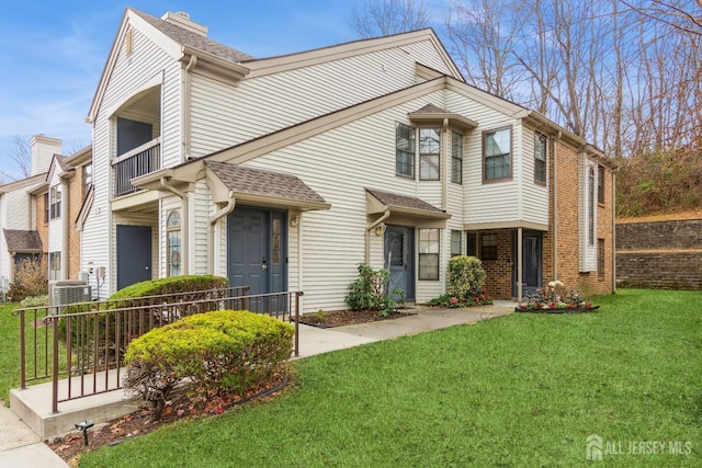 view of front of home featuring a balcony, cooling unit, and a front lawn