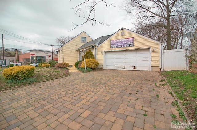 view of front of home featuring fence, an attached garage, and decorative driveway