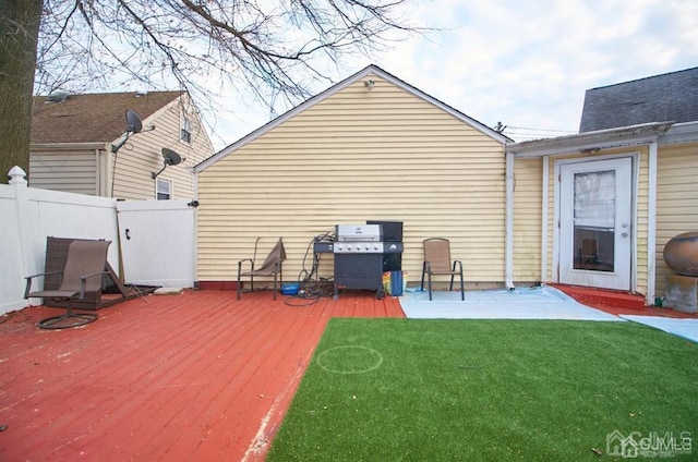 rear view of house featuring a lawn, a wooden deck, and fence