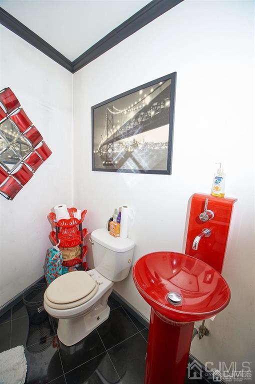 bathroom with crown molding, tile patterned floors, and toilet