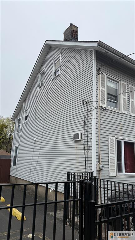 view of side of home featuring fence and a chimney