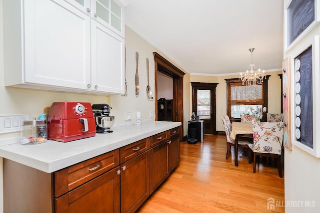 322 2nd St, Middlesex, NJ 08812 - kitchen featuring a chandelier, light wood-type flooring, crown molding, white cabinetry, and light countertops